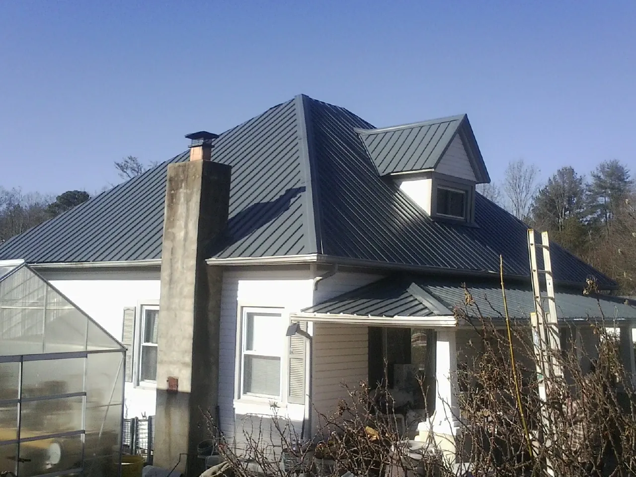 Dark blue standing seam metal roof on a white farmhouse with dormer — Slate & Tile Roof Repair by Roofing Brothers in Fishs Eddy