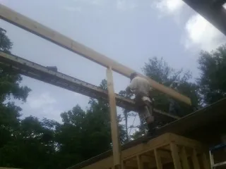 Carpenter setting a ridge beam over a new addition frame in Fishs Eddy