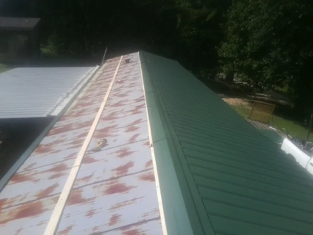 Old rusted panels beside newly installed green metal roofing — Wind Damage Roof Repair by Roofing Brothers in Fishs Eddy