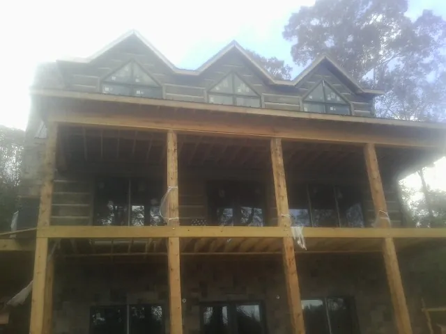 Dormers and porch framing on a large log home under construction — Roof Coating work by our crew in Fishs Eddy