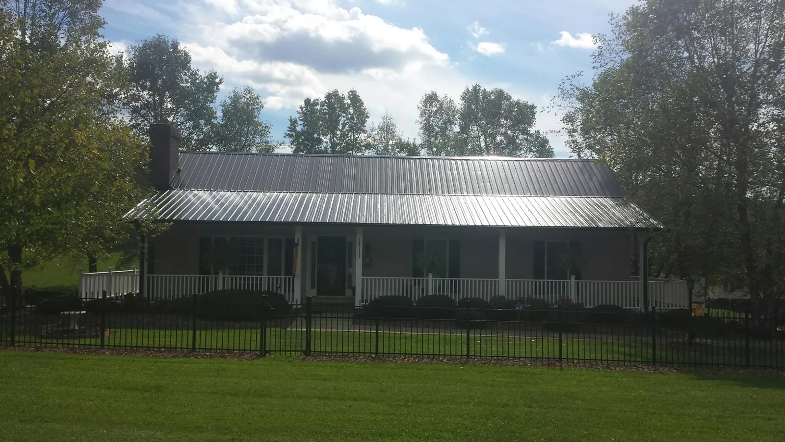 Gray metal roof on a brick ranch with a full width front porch — Gutter Guard Installation work by our crew in Fishs Eddy