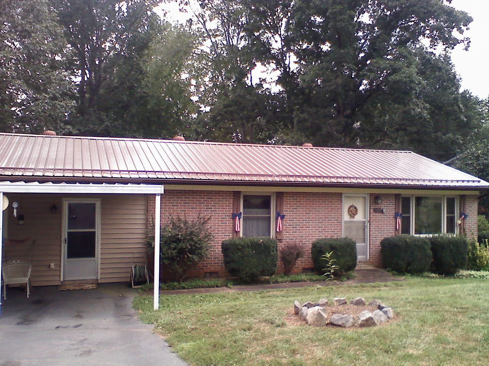 Bronze metal roof and carport on a brick ranch home — Roof Repair work by our crew in Fishs Eddy