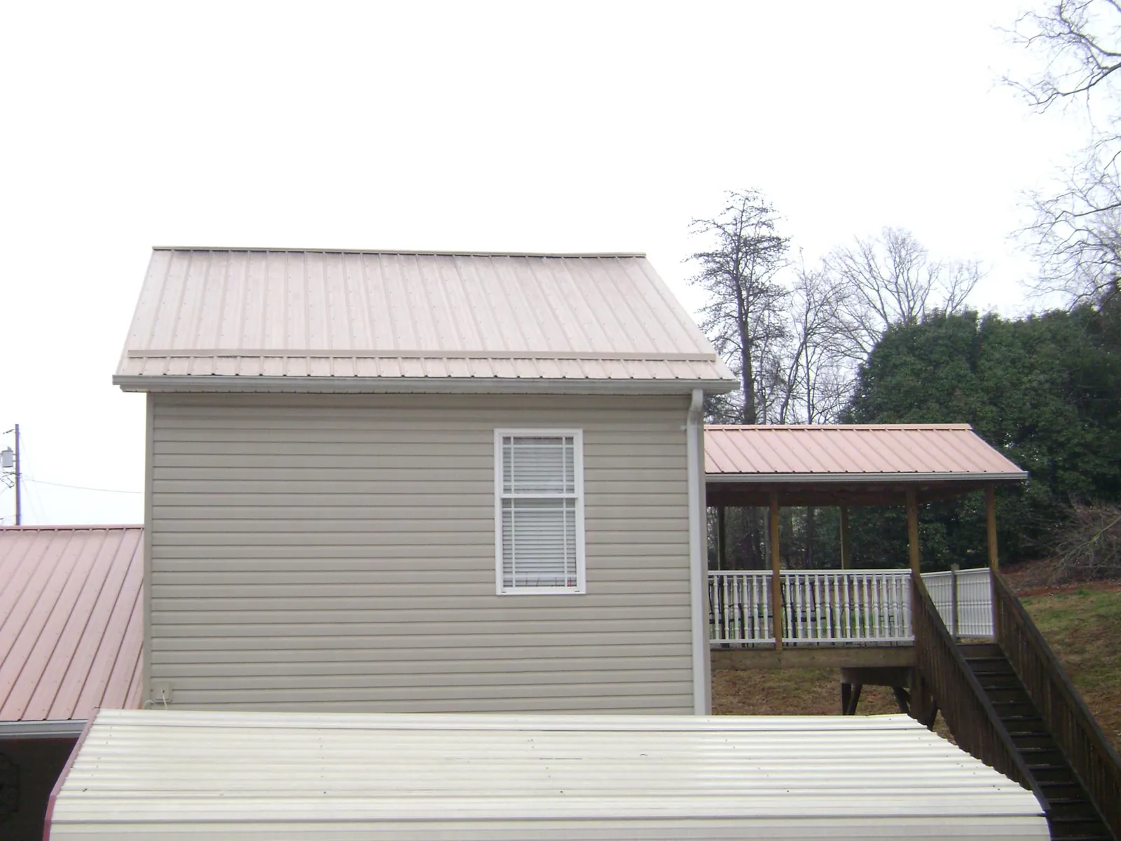 Tan metal roofs on a two story addition and attached porch, from a Roof Replacement job in Fishs Eddy