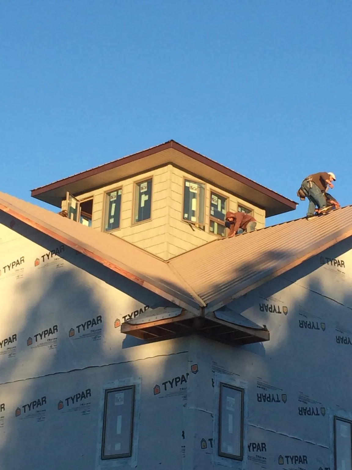 Roofers working around a rooftop cupola on a new metal roof at sunset — Roof Waterproofing in Fishs Eddy by Roofing Brothers